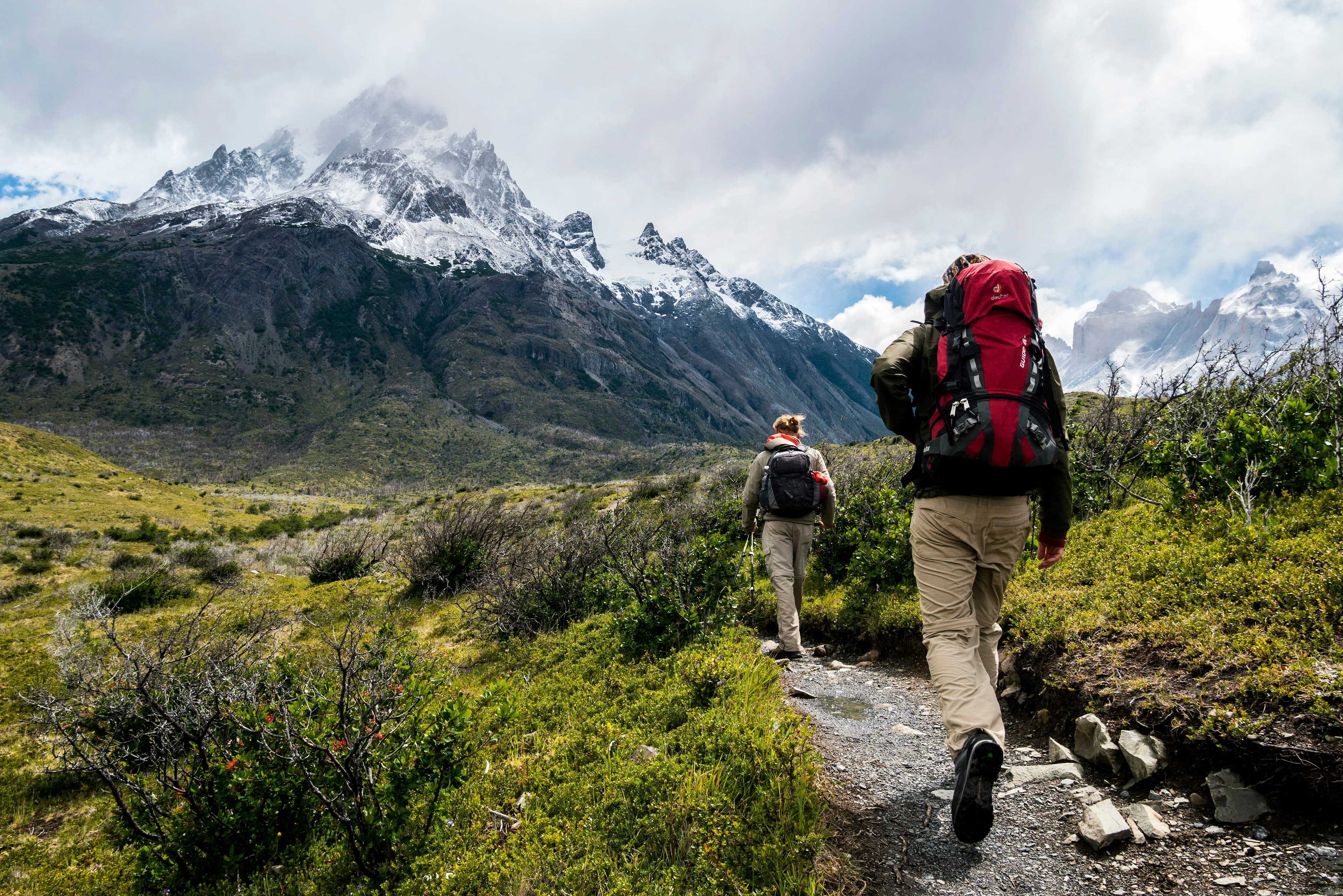 Hiker with a budget hiking backpack ascending a rocky mountain trail at golden hour